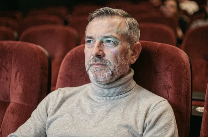 Un homme senior installé dans un fauteuil de cinéma profitant d'une séance à tarif réduit